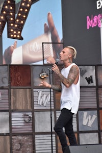 a man with tattoos standing on stage with a microphone
