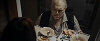 a man holding a tray of food in front of a woman