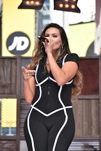 a woman in a black and white jumpsuit singing into a microphone