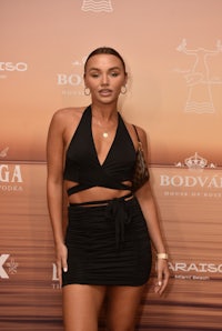 a woman in a black dress posing on the beach
