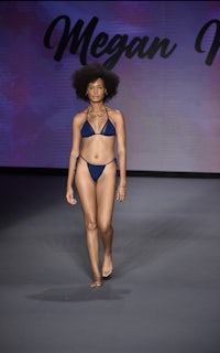 a woman in a blue bikini walks down the runway