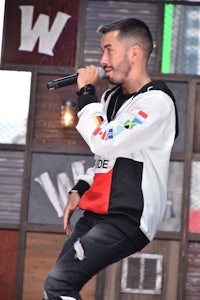 a man in a hoodie singing into a microphone