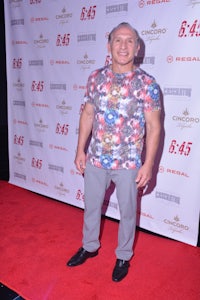 a man in a floral shirt standing on a red carpet