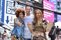 three people posing for a picture in front of a billboard