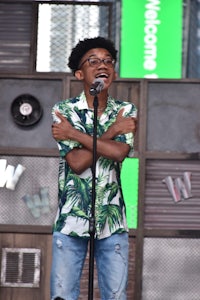 a young man in a green shirt singing into a microphone