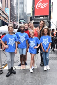 a group of girls in blue t - shirts posing for a photo in times square