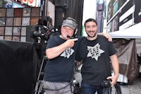 two men posing in front of a camera in times square