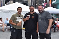 three men standing in front of a tent in times square
