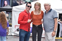 three people posing for a picture in front of a tent