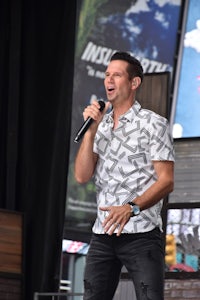 a man in a white shirt singing into a microphone