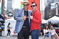 two men posing for a photo in times square