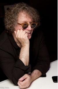 a man with curly hair and sunglasses sitting at a table