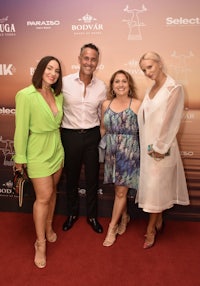 four people posing for a photo on a red carpet